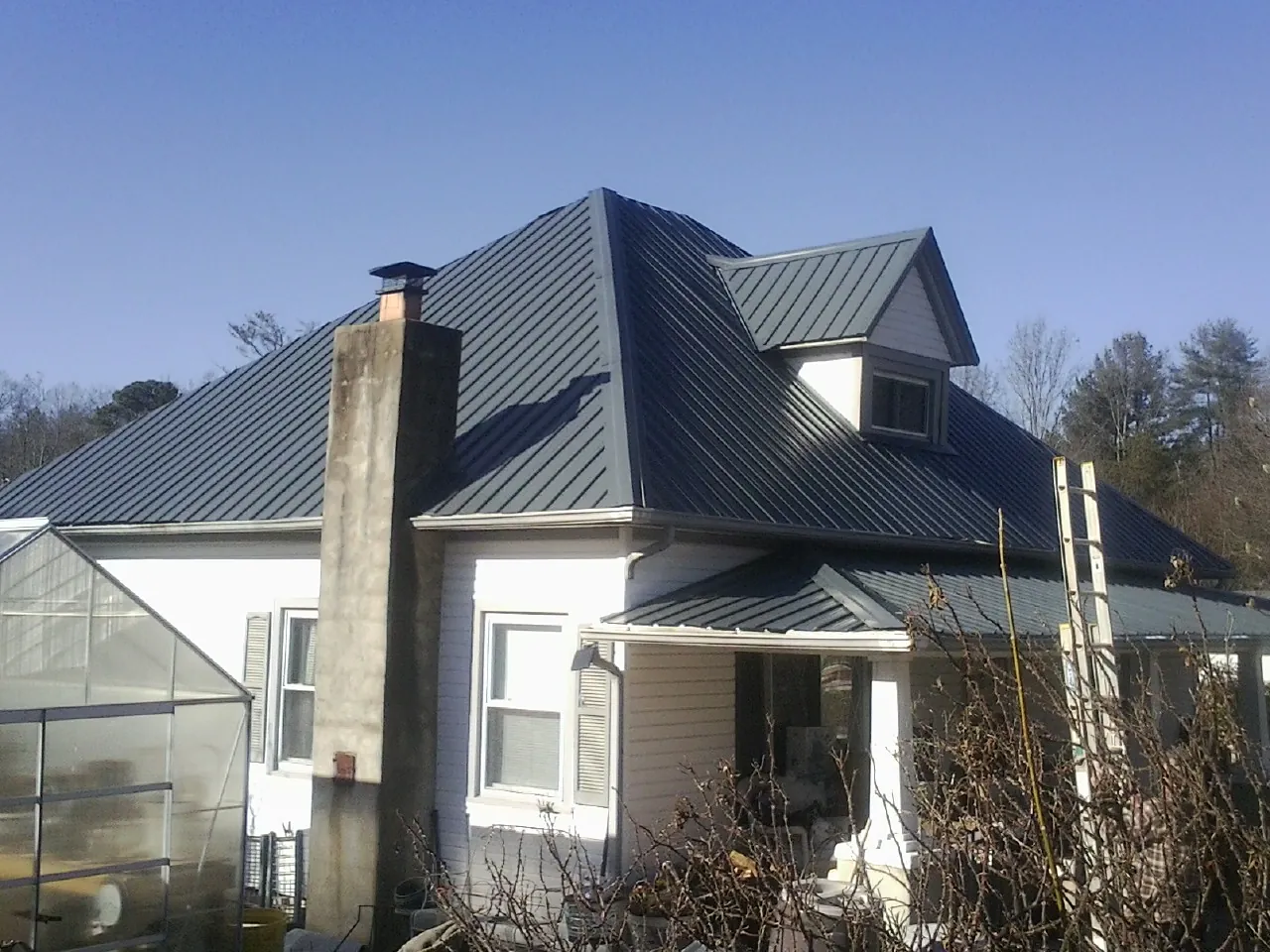 Dark blue standing seam metal roof on a white farmhouse with dormer — Slate & Tile Roof Repair by Roofing Brothers in Spray