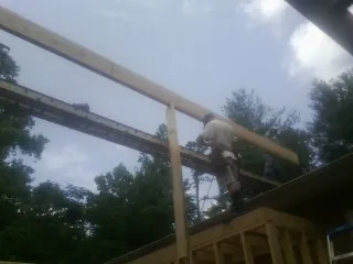 Carpenter setting a ridge beam over a new addition frame — Ice Dam Removal by Roofing Brothers in Spray