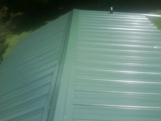 New green metal panels meeting at the ridge of a roof — Flat Roof Repair work by our crew in Spray