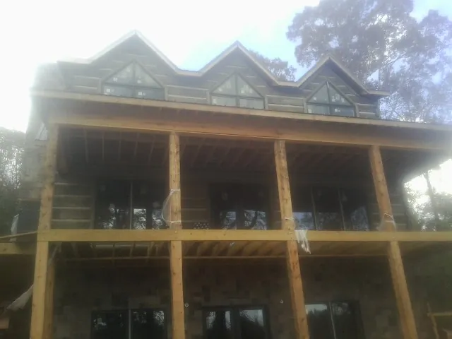 Dormers and porch framing on a large log home under construction — Roof Coating work by our crew in Spray