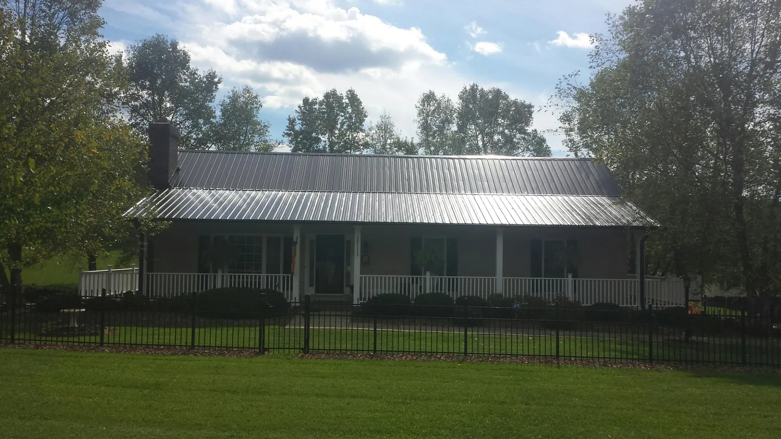 Gray metal roof on a brick ranch with a full width front porch — Gutter Guard Installation work by our crew in Spray